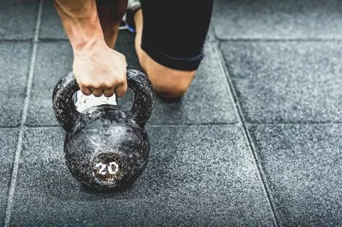 Muscular woman holding old and rusty kettlebell on to the gym floor Stock Photos