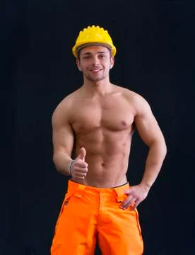 Muscular young construction worker doing thumb up sign for ok Stock Photos