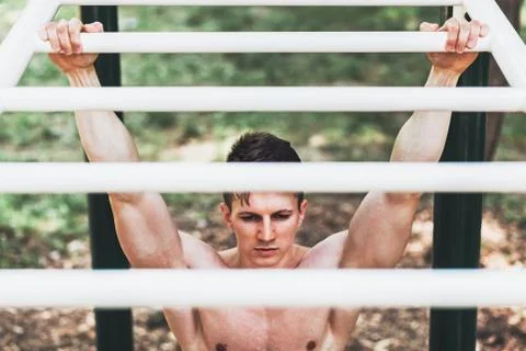 Muscular young man doing pull ups exercises Stock Photos