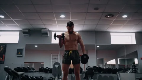 The muscular young man, with an empty chest, trains his muscles by lifting Stock Footage 156867329