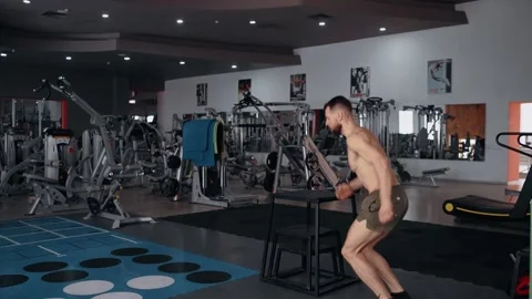 The muscular young man performs the jump on the iron chair, descends on the Stock-Footage 156871063