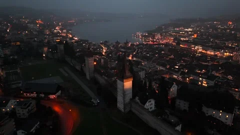 Musegg Wall and its nine towers aerial view at night overlooking glowing city in Stock Footage 336750890