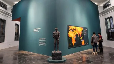 Museum Exhibit of Human Evolution Featuring Statue and World Migration Map Stock Photos
