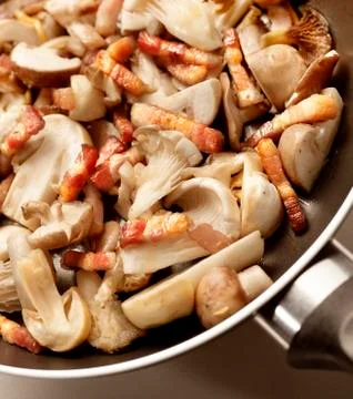 Mushrooms and bacon cooking in a frying pan Stock Photos