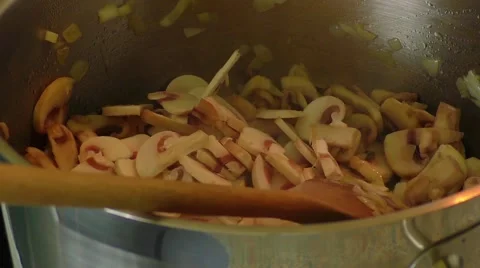 Mushrooms being sauteed in a pan using a wooden spoon Stock Footage 58282786