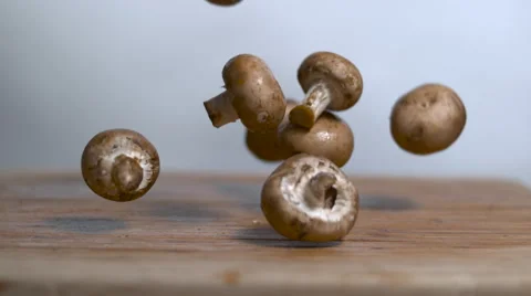 Mushrooms dropping in slow motion onto a cutting board - static shot Stock Footage 64120180