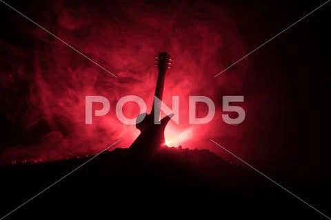 Music concept. Acoustic guitar isolated on a dark background under beam of li Stock Photos