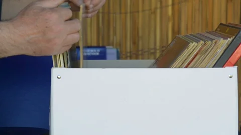 Music fan watches a stack of old 33 rpm vinyl records. A disc is carefully re Video stock 109086865