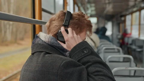 Music maker focused. Individual adjusting headphones in tram carriage. Artist Stock Footage 345165800