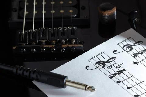Music note and jack cable on black electric guitar in darkness. Stock Photos