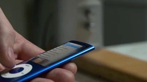 Music player in male hand, on home interior background. Toggles the music on the Stock Footage