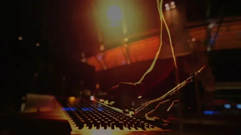 Music producer adjusting console knobs under spotlight, LED lights with animated Video stock 307652306