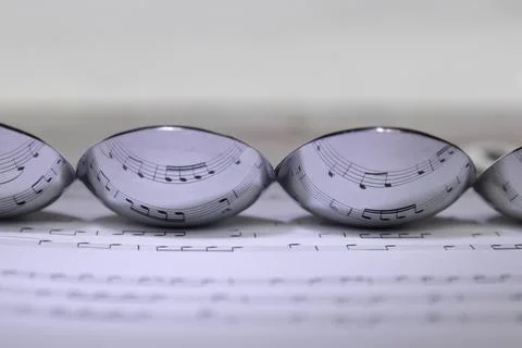 Music reflected in the underside of spoons Stock Photos