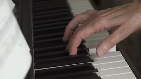Music sheet and pan moving to an old person hand playing the piano. Stock Footage 141363668
