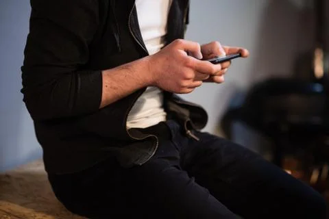 In a music Studio a guy sits on a table and plays a video game on his phone Stock Photos