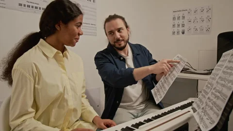Music Teacher Explaining Sheet Music to Female Student at Piano Stock Footage 339203586