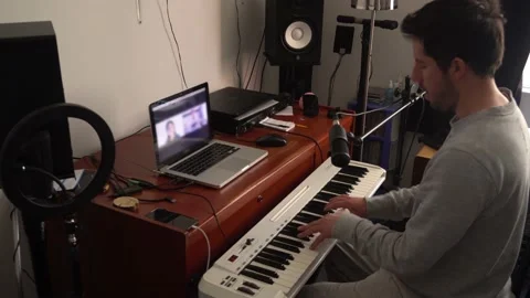 A music teacher giving virtual classes with his laptop and paino in his room Stock Footage 164583002