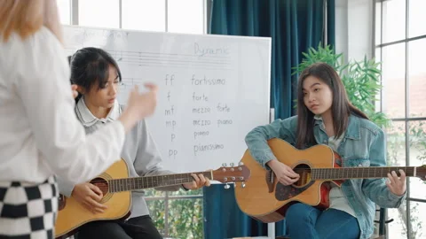 Music teacher is passionately teaching note reading and guitar chords correctly Stock Footage 276574400