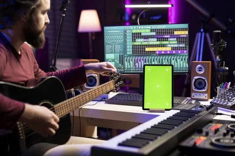 Musical engineer learning to tune his acoustic guitar before playing Stock Photos
