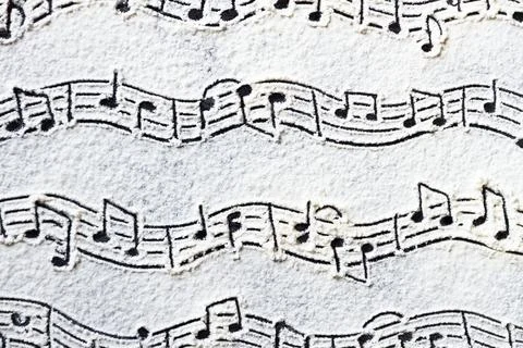 Musical notes pattern printed on white flour sand, powder on dark table. Natu Stock Photos