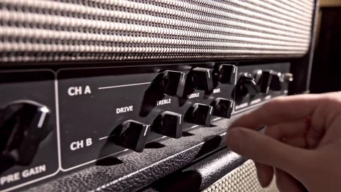 Musician adjust amplifier knobs to fine tune the output sound 動画素材 122584990
