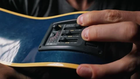 Musician Adjusting Equalizer Preamp Controls on Blue Acoustic Electric Guitar Stock Footage 339367046