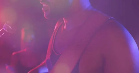 Musician adjusting strap, pullback showing vocalist singing into mic for music Stock Footage 331235336
