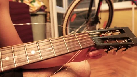 Musician changing strings on a classic acoustic guitar at home Stock Footage 341376524