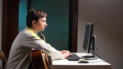 Musician composing music on computer with guitar nearby Stock-Footage 308967686