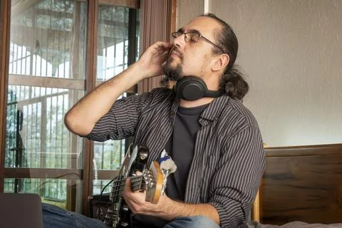 Musician Listening Critically While Practicing Electric Bass at Home Stock Photos