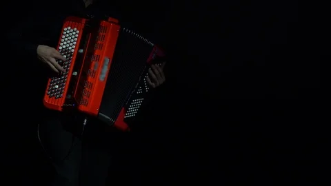 Musician man without face playing the red accordion on black background close up Stock Footage 119979938