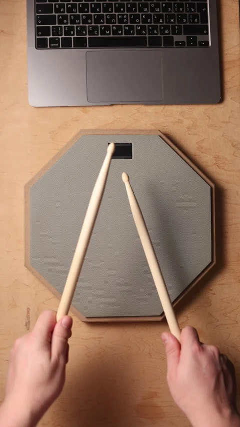 Musician practicing drumming on a pad with laptop nearby for inspiration Stockbeeldmateriaal 341737898