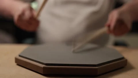 Musician practicing drumming on a practice pad with sticks Stockbeeldmateriaal 341737435
