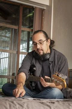 Musician Practicing at Home While Reading Sheet Music and Playing Electric Bass Stock Photos