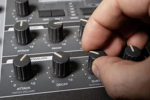 A musician turns the knobs of a synthesizer to adjust the sound. Close-up. Foto stock