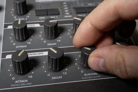A musician turns the knobs of a synthesizer to adjust the sound. Close-up. Foto stock