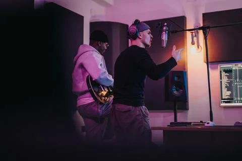 Musicians collaborating in a modern recording studio with vibrant lighting Stock Photos