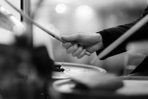 The musician's hand during performance of a composition on a drum set Stock Photos