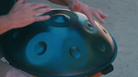 Musician's hands playing a handpan, a melodic percussion instrument creating a r Stock Footage 336466855