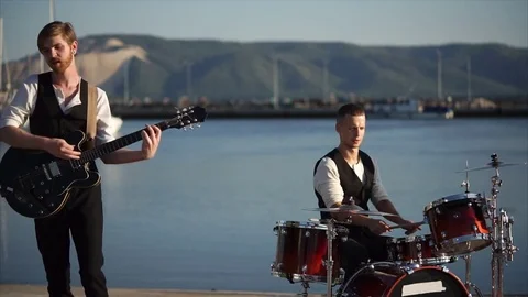 Musicians playing drums and guitar during outdoor band performance Stock Footage