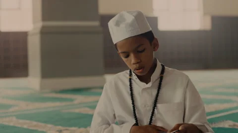 Muslim boy reading something from a book Stock Footage 279709196