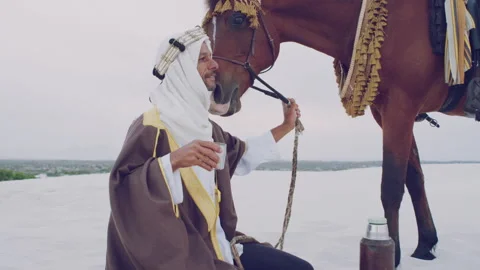 A Muslim doing a prayer next to his horse during the day Stock Footage 279715657