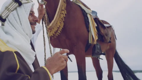 Muslim doing a prayer next to his horse on a windy day Stock Footage 279719691