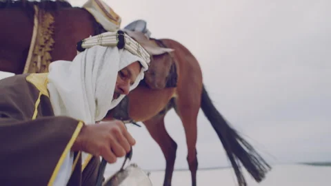 Muslim doing a prayer next to his horse in the desert Stock Footage 279720972