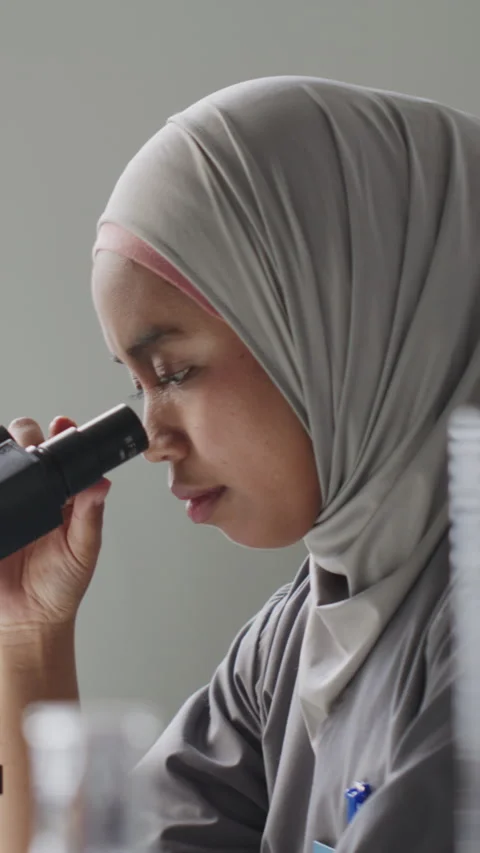 Muslim Female Scientist Observing Sample through Microscope in Laboratory Stock Footage 312473074