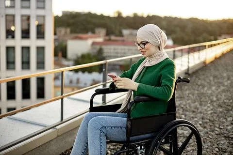 Muslim lady with mobility issues using phone outside home Stock Photos