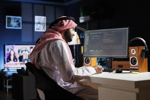 Muslim man checks database code on pc Stockfoto's