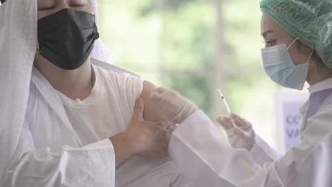 Muslim man looking at while get covid vaccine from hand nurse injecting vaccine. Stock Footage 163567765