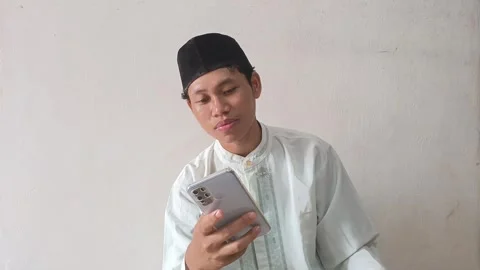 Muslim Man Smiling While Looking at Smartphone Indoors Stock Footage 317025777