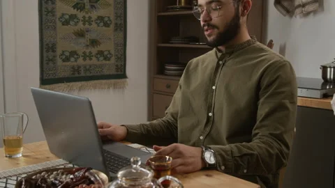 Muslim Man Using Laptop for Online Meeting in Modern Kitchen Stock Footage 331826749